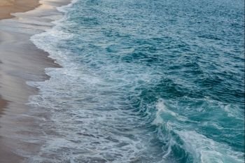Foamed blue waves breaking in the beach