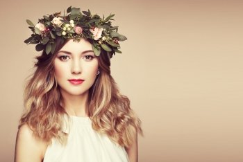 Beautiful blonde woman with flower wreath on her head. Beauty girl with flowers hairstyle. Perfect makeup. Beauty fashion. Spring woman