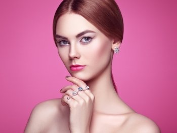 Fashion portrait of young beautiful woman with jewelry. Blonde girl. Perfect make-up and hairstyle.  Beauty style woman with diamond accessories. Pink background