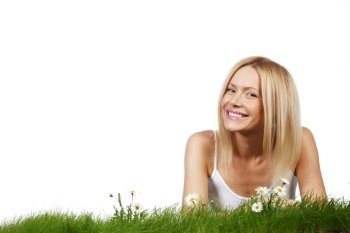 Beautiful young blonde woman lying on grass with chamomile flowers, isolated on white background