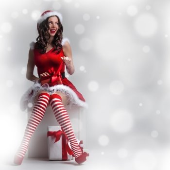Christmas woman with gift. Beautiful pin-up Christmas woman in Santa Claus costume unpack gift