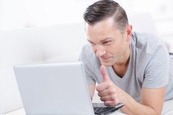 man holding laptop and thumbs up indoor