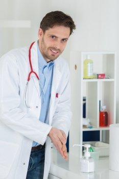 medical doctor using sanitizer dispenser in clinic