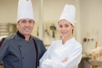 a male and female chef posing in restaurant kitchen