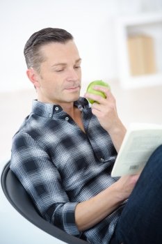 man eating an apple while reading