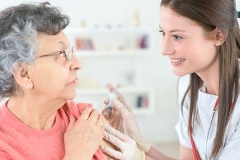 doctor inject influenza vaccine into old woman patient