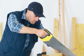 handyman cutting wood with hand saw