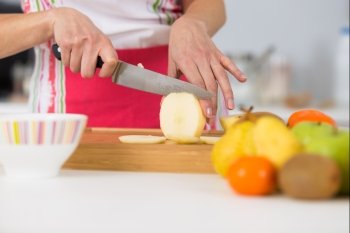 close-up on mature female hands slicing apples on chopping board