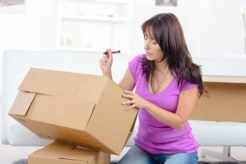 woman writing with pen on shipping box