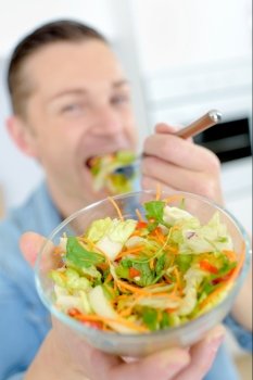 Man eating salad, showing bowl