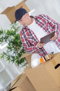 middle age man packing cardboard box with sellotape