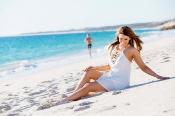 Young woman sitting on the beach. Portrait of young pretty woman sitting on the beach