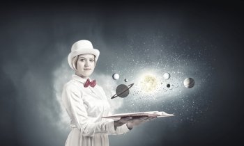 Pretty woman studying astronomy. Young woman in white cylinder and red bowtie with book in hands