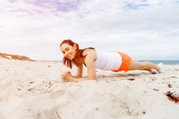 Young woman training on beach outside. Young woman training alone on beach outside