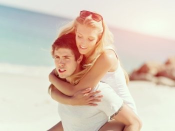 Portrait of man carrying girlfriend on his back. Portrait of man carrying girlfriend on his back on the beach