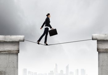 Risky businesswoman. Young confident businesswoman walking on rope above gap