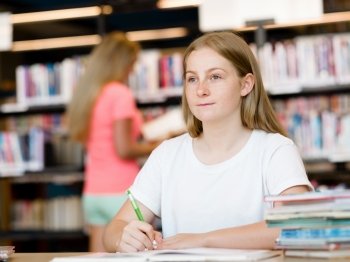 Teenage girl with books studying in library. Teenage girl with books
