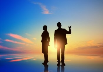 Silhouettes of business people standing on sunset background . They are proffesionals