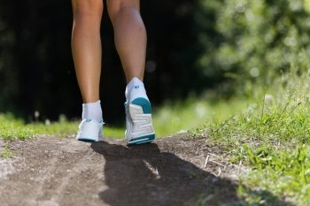 Sport woman. Close up of female feet running on road