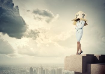 Woman with box on head. Businesswoman standing on top of building with carton box on head