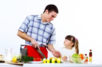Happy young family with a daughter cooking together at home