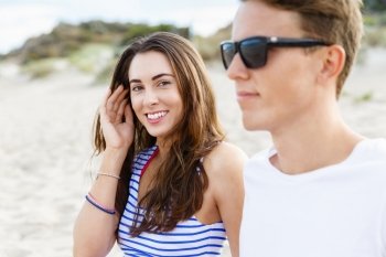 Romantic young couple sitting on the beach. Romantic young couple sitting on the beach . Girl looking at camera