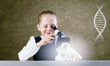 School girl at lesson. Cute school girl with microscope against blackboard with formulas