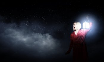 Lost in night. Young woman in red cloak with lantern lost in forest
