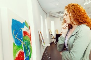 Young caucasian woman in art gallery front of  paintings. Young caucasian woman in an art gallery in front of painting displayed on white wall