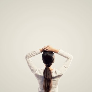 Young woman standing with back. Image of young woman standing with her back with arms above head. Place for text