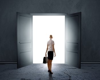 New opportunities. Rear view of businesswoman standing in light of opened door