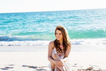 Young woman sitting on the beach. Portrait of young pretty woman  sitting on sandy beach