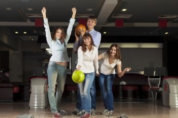 Group of four young smiling people playing bowling. Weekend with friends