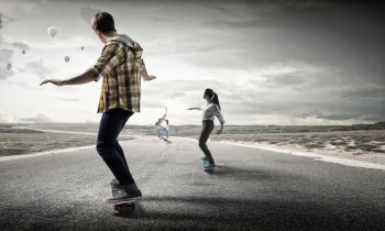 Teenagers ride skateboard. Active teenagers riding skateboard on asphalt road
