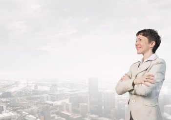 Successful smiling businesswoman. Confident businesswoman with arms crossed on chest on modern city background