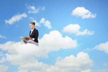 Business break. Young attractive businesswoman sitting on cloud and reading book