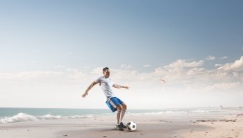 Soccer player hitting ball. Football player with ball in action at ocean coast