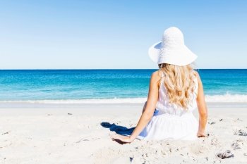 Young woman relaxing on the beach. Portrait of young pretty woman in white relaxing on sandy beach