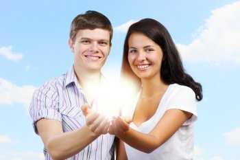 Creativity concept. Young happy couple holding electric bulb in palms