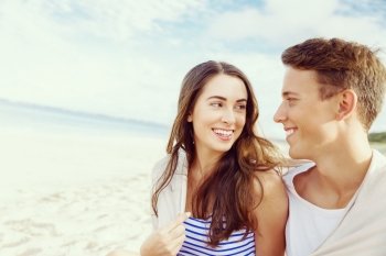 Romantic young couple sitting on the beach. Romantic young couple sitting on the beach looking at each other