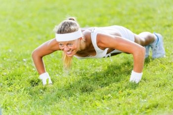 Outdoor workout. Young attractive sport girl in park doing push ups