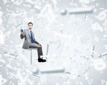 Internet communication. Young businessman sitting on huge white letter. Email concept