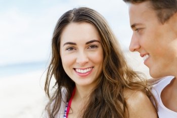 Romantic young couple sitting on the beach. Romantic young couple sitting on the beach. Girl looking at camera