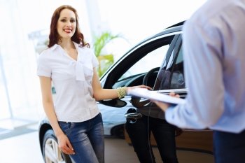 Young woman at car salon. Attractive woman at car salon with consultant choosing a car