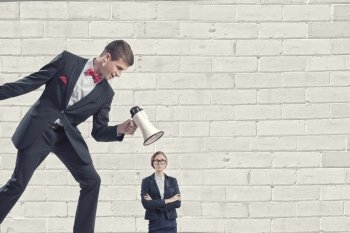 Aggression and humiliation in communication. Aggressive businessman screaming in megaphone on her colleague