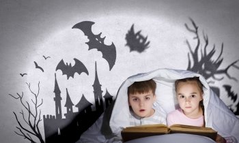 Children’s nightmares. Children sitting in bed under blanket with book
