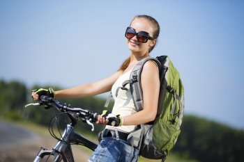 Young beautiful woman riding a bicycle in a park. Summer bike walk