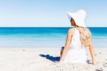 Young woman relaxing on the beach. Portrait of young pretty woman in white relaxing on sandy beach