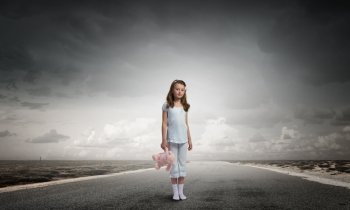 Little girl with bear. Cute girl wearing pajamas with toy bear in hand standing on road