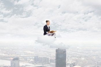 Business break. Young attractive businesswoman sitting on cloud and reading book